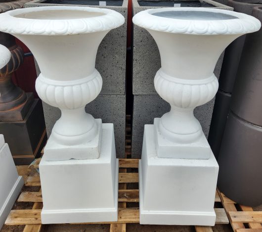 Two GardenLite Classic Urn White 51x64cm sitting on a pallet.