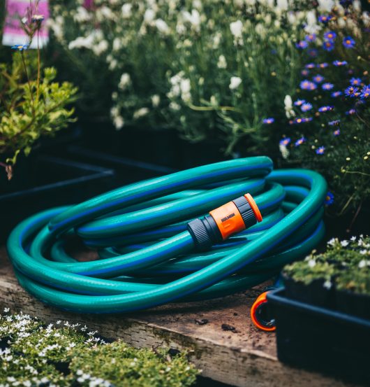 A Hose with Fittings and Tap Connectors 18mmx10m laying on a wooden bench.