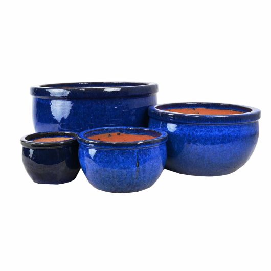 Four blue ceramic pots of varying sizes are displayed, each with a glossy finish and empty interiors. Among them is a striking Glazed Roll-Top Planter Moss Green XL 58x 48cm (Copy), seamlessly blending into the elegant arrangement.