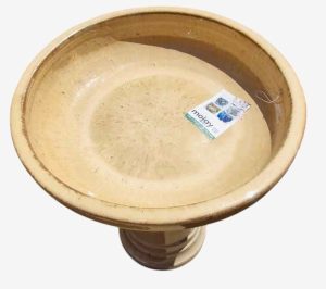 A round, beige birdbath filled with water, featuring a Sorrento Birdbath Cream 46x60cm label inside.