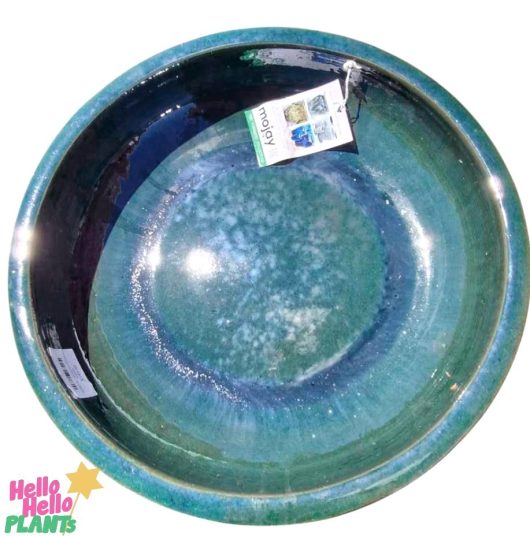 A large, round ceramic bowl with a glossy blue and green Iridami-like finish, resembling the Sorrento Birdbath Bottle Green 46x60cm. A tag is attached to the rim.