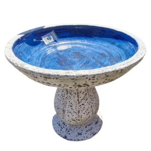 A round, speckled birdbath with a wide, deep blue basin and a sturdy pedestal base.