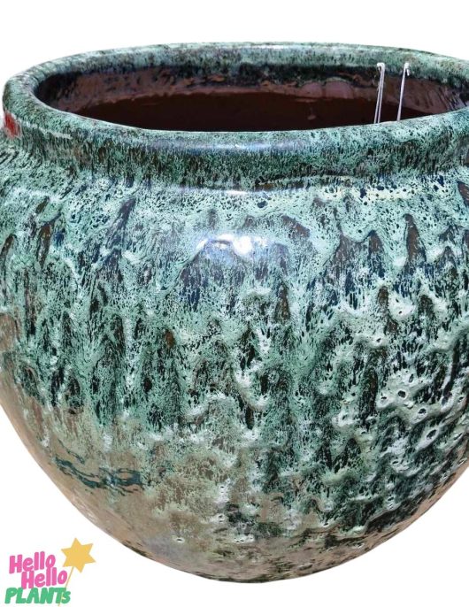 The Sorrento "Sadiki Urn Antique" M 40x36cm is a large green ceramic planter with a stunning drip glaze finish, reminiscent of an antique urn. The logo is elegantly placed at the bottom left corner, enhancing its exquisite design.