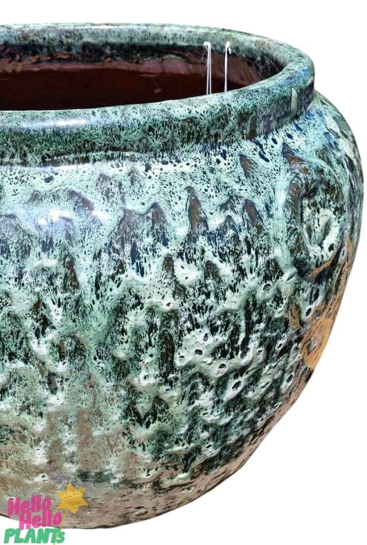 A large ceramic pot, textured and green with speckled patterns, reminiscent of the Sorrento 'Sadiki Urn Antique' M 40x36cm.