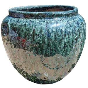 A large, round ceramic Sumbawa Stone Tropman pot in a mottled green and brown glaze features an iridami relief, adding subtle elegance.