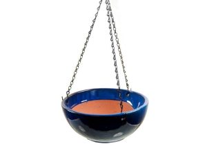 A blue ceramic hanging planter with a terracotta interior, suspended by three metal chains against a plain white background.